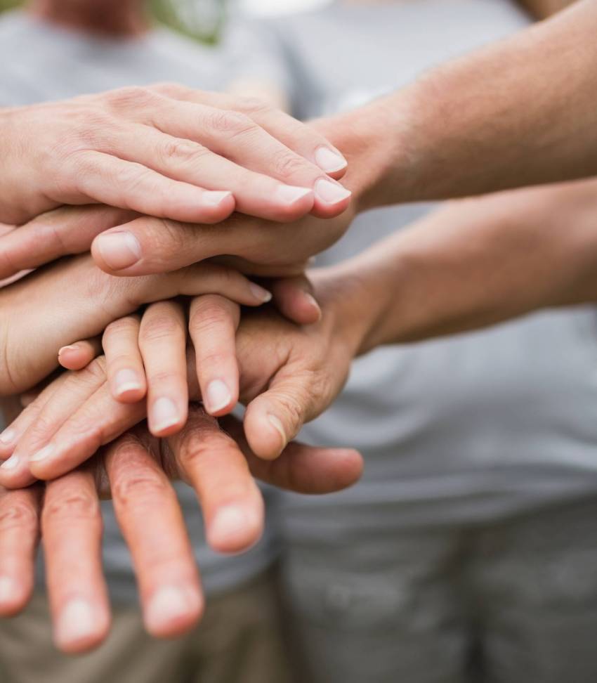 Happy volunteer family putting their hands together on a sunny day